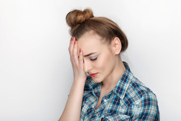 Fototapeta premium Beauty portrait of young adorable fresh looking blonde woman with high bun hair chaos in blue plaid shirt. Emotion and facial expression concept.