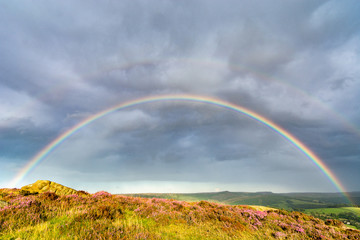 Stunning full rainbow with dramatic storm clouds in the English Peak District.