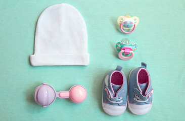 baby stuff is on a blue background. top view closeup. things little girl, pacifier, rattle, hat, and shoes.newborn baby necessities