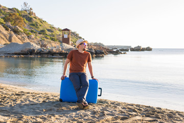 Young man holding luggage at the sea. Travel, summertime, holidays and people concept.