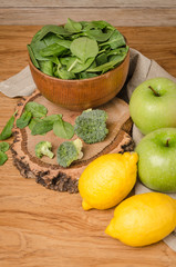 Spring spinach leaves in the bowl, broccoli, lemons and apples