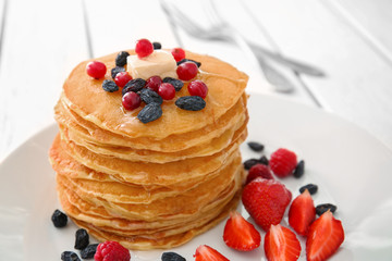 Plate with delicious pancakes on table