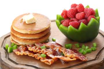Tasty breakfast with pancakes, bacon and raspberry on wooden board