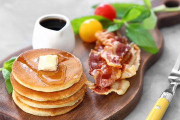 Pancakes with butter and bacon on wooden board
