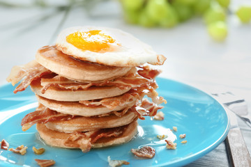 Tasty breakfast with fried egg, pancakes and bacon on table