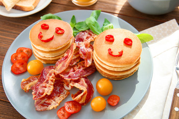 Creative tasty breakfast with pancakes and bacon on table