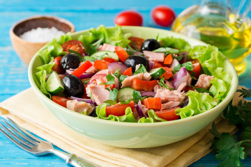 Salad with vegetables and tuna on rustic blue wooden table