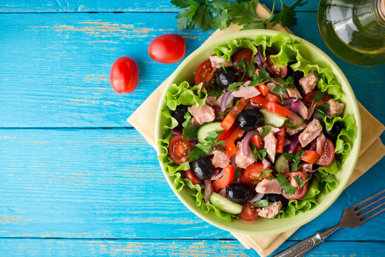 Salad with vegetables and tuna on rustic blue wooden table