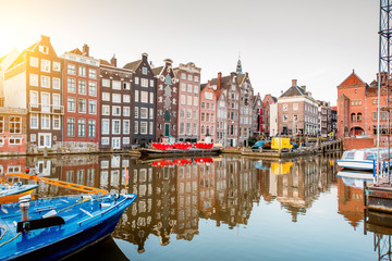 Fototapeta premium Morning view on the beautiful buildings and boats on the Damrak avenue in Amsterdam