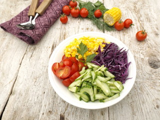 Ingredients of a vegetarian salad in a bowl. Shredded red cabbage, cucumbers, corn and tomatoes