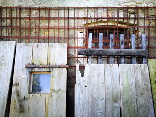 Alte Holztüren und rostiges Eigengitter vor einem ehemaligen Kuhstall auf einem alten Bauernhof im...