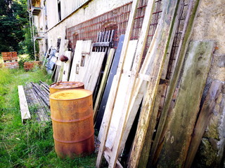 Holzlatten, Türen und rostige Fässer vor dem alten Kuhstall eines Bauernhof im Sommer im...