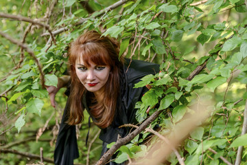 young forest fairy looks through dense forest branches