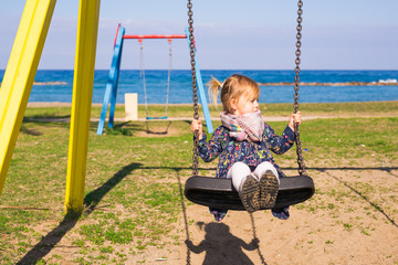 Happy child girl on swing in summer day