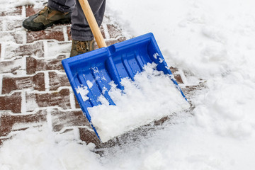 Man removing snow from the sidewalk after snowstorm