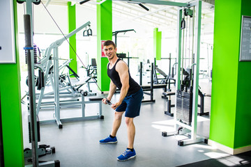 Handsome man exercising in trainer for triceps muscles in the gym