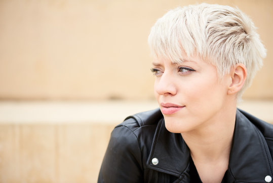 Short hair blondie in black leather jacket looking away.