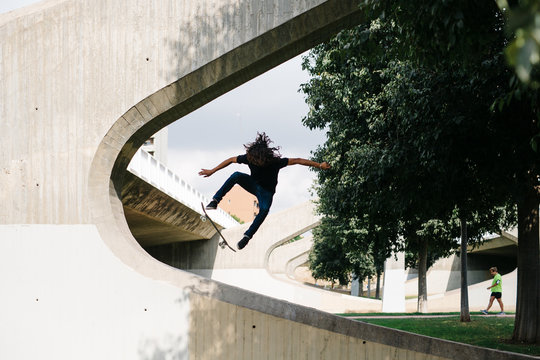 Long haired man making a trick on skateboard.