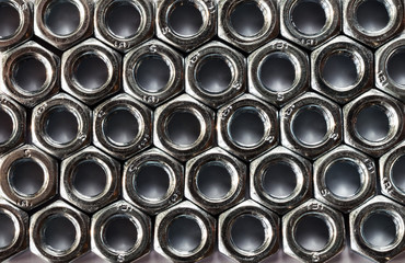 Background of identical nuts with thread. Metal texture.