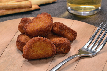 Deditos de pollo empanado y saldas sobre plato de madera.