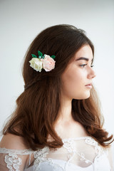 The bride on a white background in a white lace dress. Beautiful natural beauty. Light makeup and loose hair. Natural.