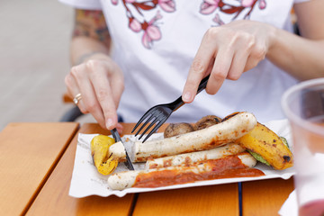 The local food festival. A beautiful girl eats fried sausages and vegetables