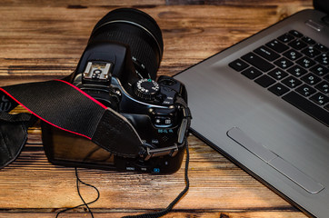 Modern DSLR camera and laptop on wooden table