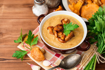 Mushroom cream soup with chanterelles and parsley on wooden background