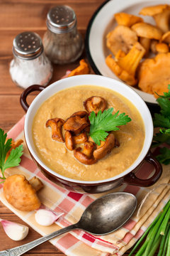 Mushroom cream soup with chanterelles and parsley on wooden background
