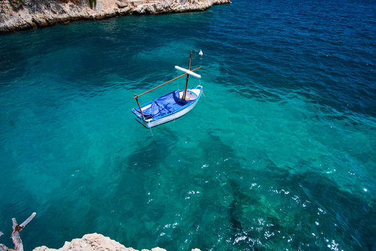 Sea water and granite stones. Boats above coral reef. Spain.