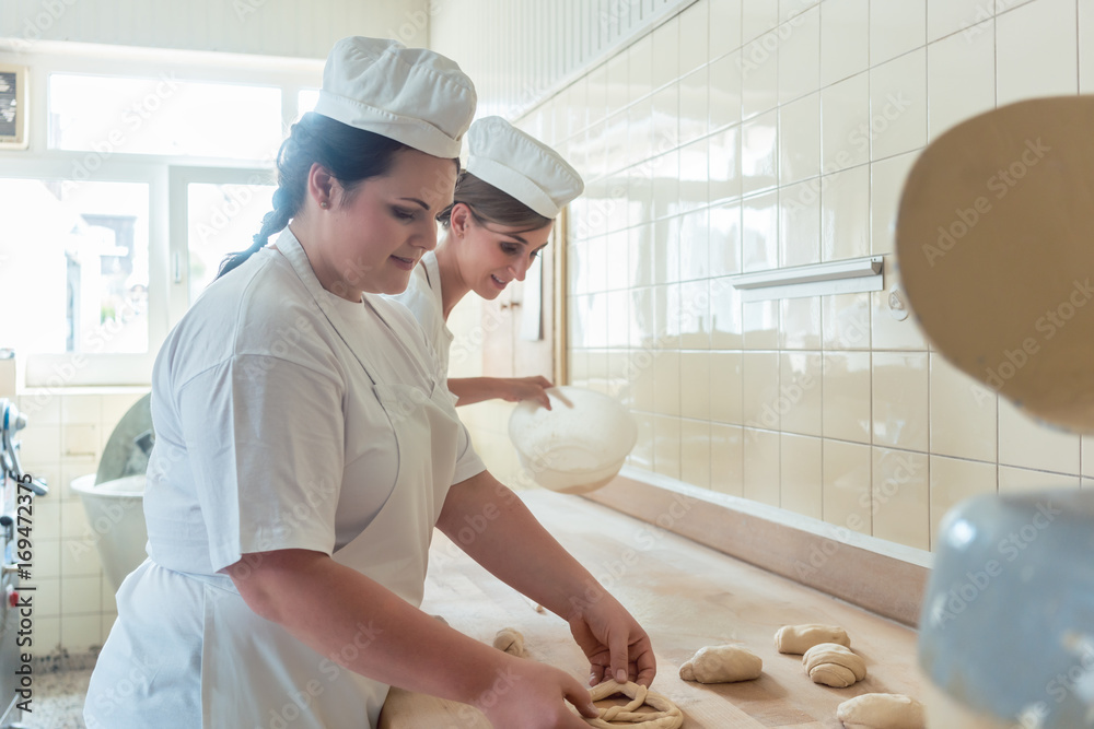 Wall mural Women in bakery forming raw dough to pretzels for later baking