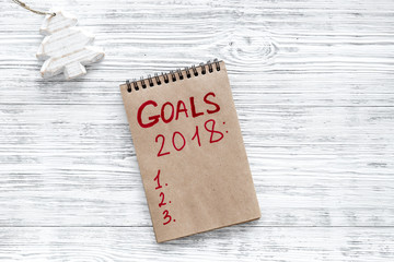 Make a goals list for 2018. Notebook and christmas decoration on wooden background top view copyspace