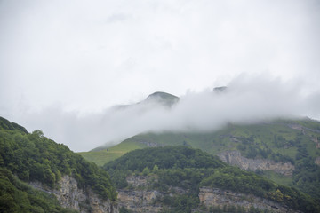 Горный пейзаж. Пасмурная погода в живописном ущелье, туман в горах, белые облака. Природа Северного Кавказа