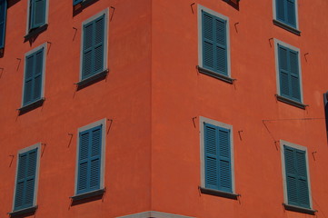 Fototapeta na wymiar Dark orange facade of building with green wooden shutters closed.