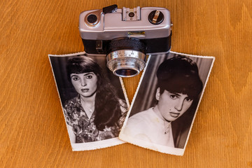 Old photos of beautiful young women and vintage camera on wooden background