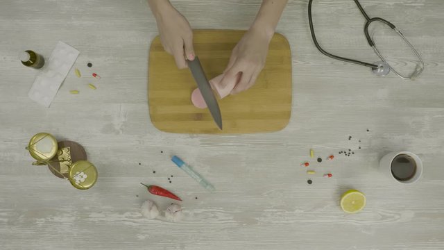 Top view of man cutting sausage or ham on the wooden stand. Top view of several slices of reduced calorie kielbasa sausage