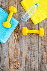 Fitness background. Dumbbells, towel and water on wooden background top view copyspace