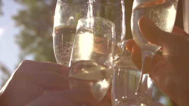 Group of people toasting and drinking champagne on the restaurant terrace over sunset. Slow motion 240 fps. 4K UHD video 3840x2160