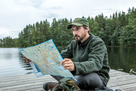 Mann liest eine Karte auf dem Bootsteg, Wandern im Linnansaari Nationalpark, Finnland 