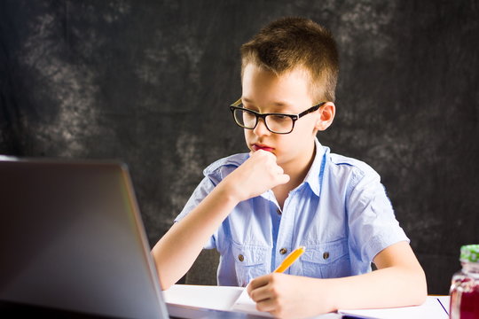 Boy doing homework with laptop at home