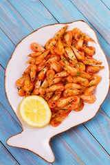 Shrimps with lemon and parsley on white plate. View from above, top studio shot