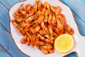 Shrimps with lemon and parsley on white plate. View from above, top studio shot