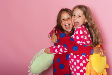 Girls in colorful polka dotted pajamas hold funny pillows
