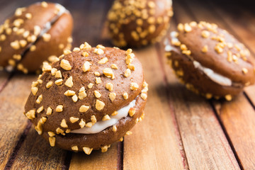 Chocolate cookies with whipped cream and nuts on wooden background