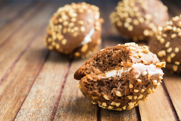Biting off chocolate cookies with nuts and cream over wooden background