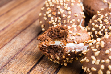 Closeup view of biting of chocolate cookie over brown wooden table with copy space