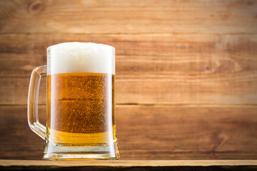 Glass with beer and chips on the background of a wooden wall.