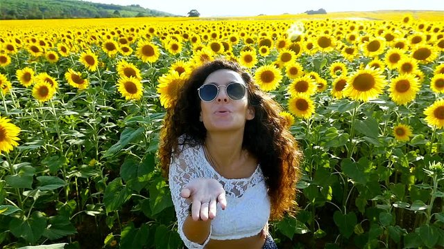 Beautiful happy girl woman giving a kiss at sunflower field in sunset. Freedom concept. Slow motion