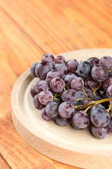 Closeup macro grapes on the round wooden kitchen board on the table