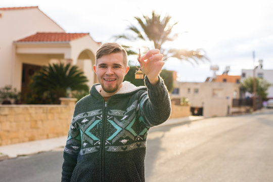 Happy young man showing off the key to his new home. Owner, real estate and people concept